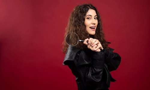 Portrait of curly girl holding magnifying glass.