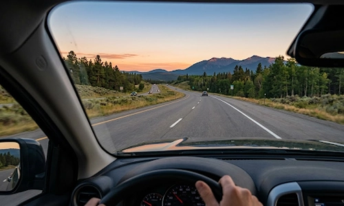 Driver's view of a scenic highway surrounded by forests and mountains without roadside billboards