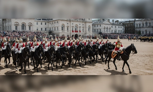 British soldiers marching in formation wearing traditional red tunics and bearskin hats during the Trooping the Colour parade.