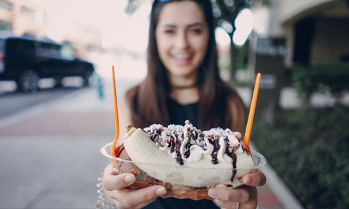 Young woman smiling while showing an ice cream dessert
