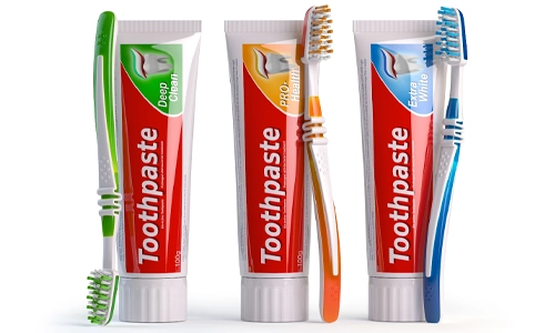 Three tubes of toothpaste, each with a different color scheme, stand next to toothbrushes with matching color schemes.