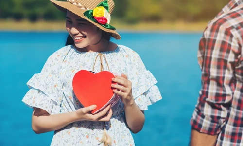 Happy young couple is holding red paper hearts